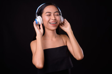 Fototapeta premium Portrait of happy young Asian woman listening to music with eyes closed