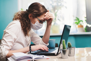 Distance learning. Online education or work. Woman in respiratory mask working at her office via laptop. Work process concept.