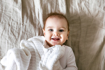 Smiling nine month old baby in bed, photographed from above