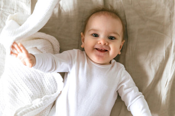 Smiling nine month old baby in bed, photographed from above