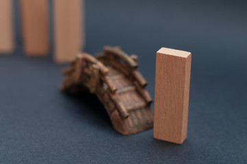 Wood block crossing a toy bridge on dark gray background. Out of the crowd, leaving the crowd, leading, social distancing, self-isolation, brain drain and human capital flight concept.
