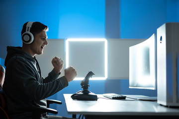 The gamer with headphones playing video games on the illuminated background © Artem