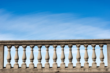 Closeup of a concrete balustrade on a blue sky with clouds and copy space