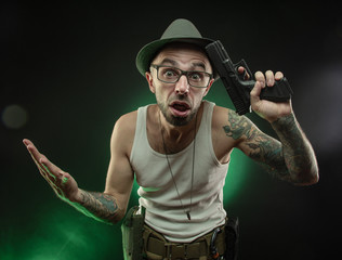 an athletic guy with a tattoo poses with a pistol