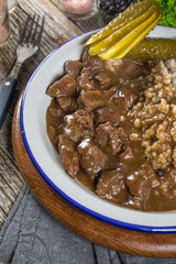 Beef stew served with barley and pickled cucumber.