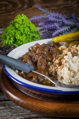 Beef stew served with barley and pickled cucumber.