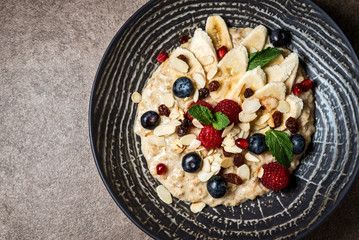Healthy porridge with raspberries, blueberries, banana and pieces of almonds.