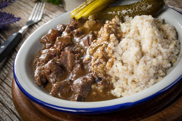 Beef stew served with barley and pickled cucumber.