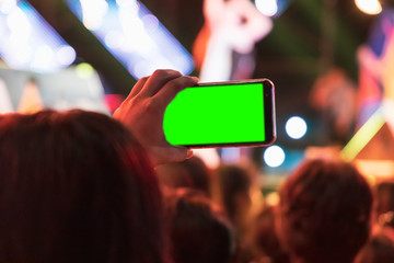 Hands of audience crowd people taking photo with mobile smart phone with green screen in party concert.