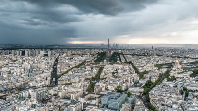Aerial timelapse of storm clouds and rain in Paris over the Eiffel Tower as traffic builds on the streets and avenues below and construction cranes work on buildings.