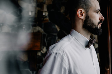 stylish young Georgian man with mustache and vintage tuxedo posing for a photo on the background of the old home
