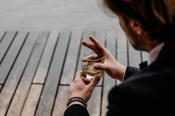 Concentrated Bearded Man Holds A Cigarette. Handsome Guy Holds A Cigarette Smoking. Bottle Of Whiskey. Side