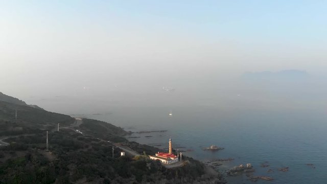 Drone flies away from lighthouse in Punta Carnero, Spain.