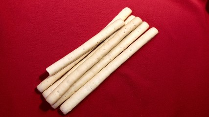 Bread cookie. Sweet bread sticks GRISSINI. Sweet sticks close up. Female hand takes bread sticks on a red background.