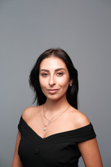 Naklejka premium A large portrait of a middle-aged woman (30-35 years old) with dark hair and brown eyes in a black dress on a light background.