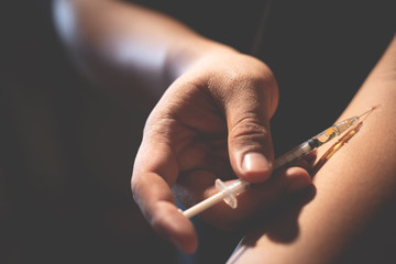 close up human hand of a drug addict and a syringe with narcotic heroin to the arm . Drugs and...