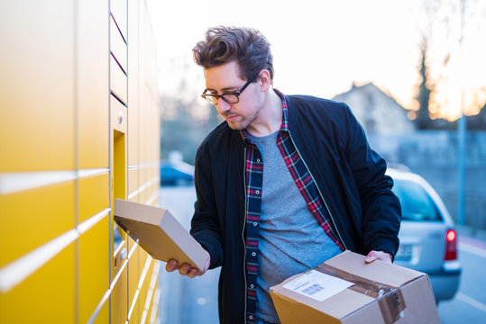 Ein Mann an einer Packstation, Pakete abholen und verschicken