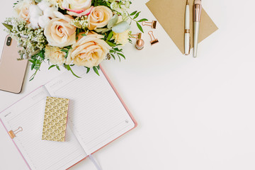 Feminine work space of blogger with beautiful bouquet of roses and opened notebook on white...