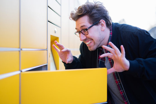 Mann holt voller Freude ein Paket bei einer Packstation ab