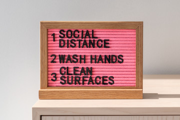 Obraz premium Coronavirus COVID-19 health safety guidelines. Text board in public space with rules, practice social distancing, wash hands often, clean surfaces, sanitizing surface, hand washing, stay home.