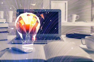 Computer on desktop in office with bulb icon hologram. Multi exposure. Concept of idea.