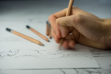 A top view flat lay of many figure drawing pencil and marker sketches. The artist worskspace with male and female drawings and pencils on the white paper, art, craft, creativity, inspiration, concepts