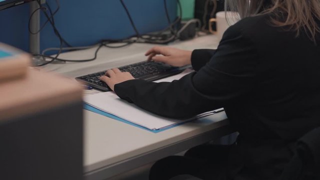 Female employee is getting ready behind her desk to start typing on her computer.