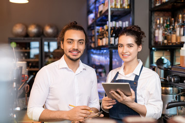 Two young smiling service staff representatives standing in front of camera