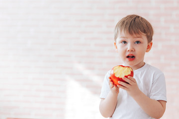 Beautiful little boy eats a fresh red apple, healthy breakfast, start the day with healthy food, than to feed the children, the freshest fruits