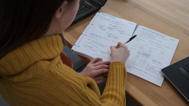 Homeschooling GCSE Student Working At Kitchen Table Physics Text Book And Computer, Coronavirus, Stay At Home, Stop The Spread.