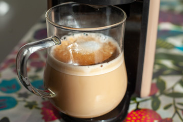transparent cup stands in a cappuccino coffee machine