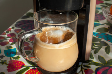 transparent cup stands in a cappuccino coffee machine
