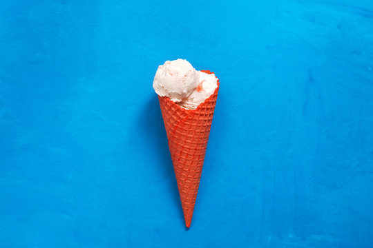 Ice cream in a red waffle cone on a blue painted background. Top view, flat lay,copy space. Summer refreshing dessert.