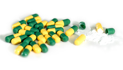 Green and yellow capsule pills on white background