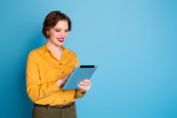 Fototapeta premium Photo of pretty business lady hold tablet hands freelancer worker reading corporate report company website wear yellow shirt green pants isolated bright blue color background