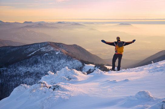 man with open arms over wonderful mountains landscape in mist during calm winter evening