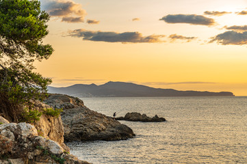 Lone Sea Fisherman on the rocks at dawn getting his rods ready