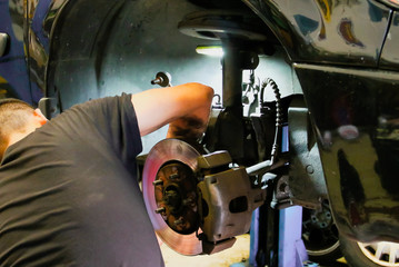 Mecánico trabajando en la reparación de la rueda de un coche en un taller mecánico de Madrid, España.