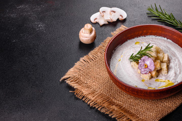 Delicious beautiful mushroom soup in a brown plate with a wooden spoon