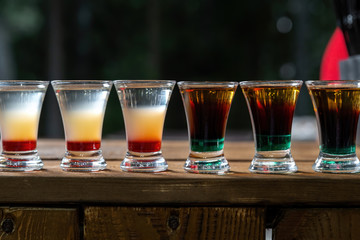 Shot drinks in row. Alcoholic shots on a wooden counter.