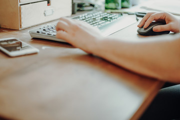 Woman typing on a keyboard working in home office.