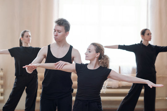 Young male instructor helping one of females with outstretched arms