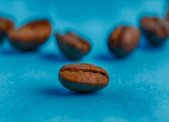 Close-up of a coffee bean on a blue background, a large bean on a background of other coffee beans