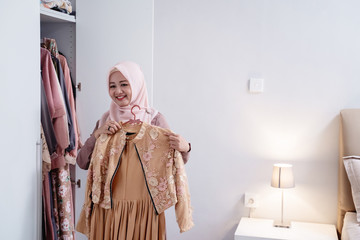 Moslem women measure a new dress by the body in front the wardrobe in the room