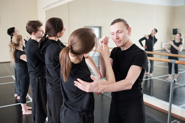 Young instructor of modern ballet dancing cource helping one of his students © pressmaster