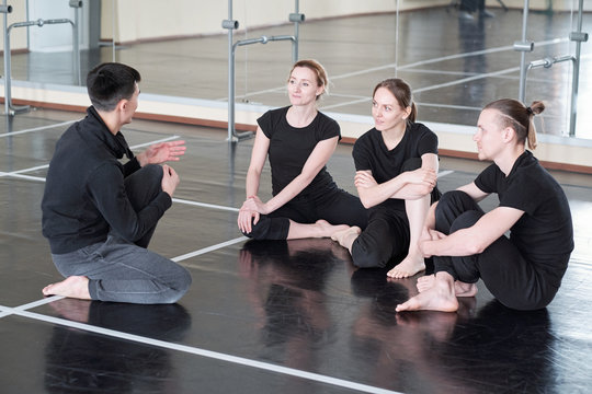 Three young students of dance course looking at groupmate during discussion