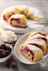 Oriental cuisine. Khanum is a dish of Uzbek cuisine. Dough with cottage cheese, sugar and cherries in the form of a roll steamed. Dish on a white plate on a light grey background. Background image
