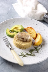 Healthy food. Quinoa with fish, avocado, lemon and rosemary on a light plate on a grey background. White napkin and fork. Background image, copy space
