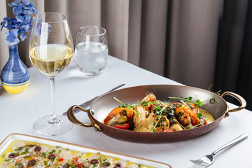 Grilled prawns shrimps with vegetables in a metal bowl on white table, side view, horizontal
