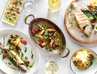 Grilled prawns shrimps with vegetables in a metal bowl and grilled fish on white table, top view, horizontal